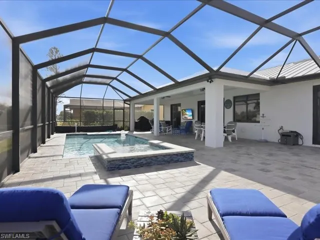 Outdoor pool with a sunroom, glass enclosure, a patio area, an in-ground hot tub, and outdoor dining space
