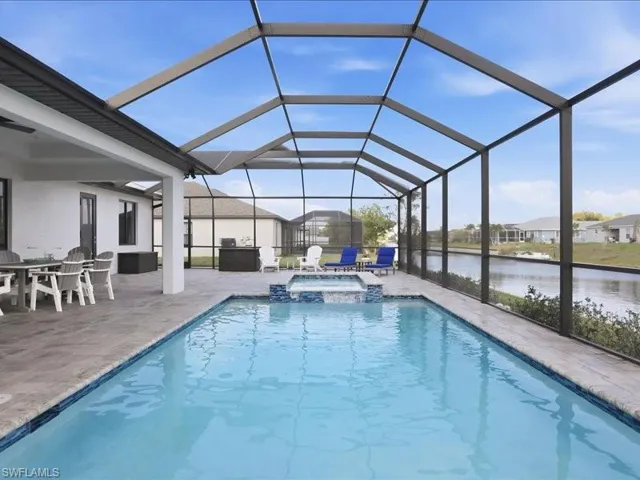 Integrated pool / hot tub with glass enclosure, a sunroom, a water view, and outdoor dining area