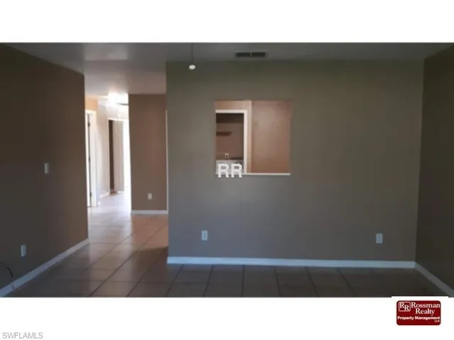 Kitchen featuring white appliances, light countertops, light tile patterned flooring, and wood finish cabinetry