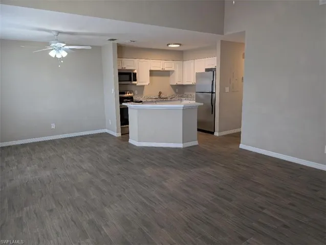 Kitchen with stainless steel appliances, ceiling fan, open floor plan, and baseboards
