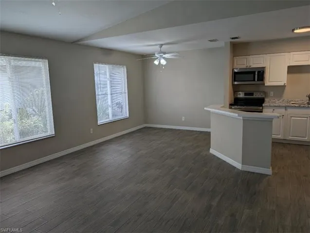 Kitchen featuring stainless steel appliances, light countertops, baseboards, and white cabinetry