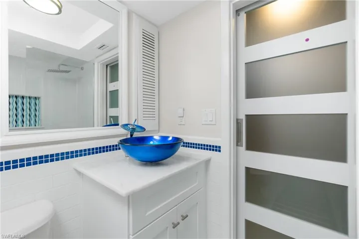 Bathroom featuring tile walls, vanity, and toilet