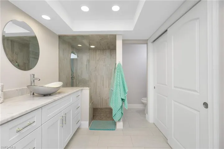 Bathroom featuring vanity, a tile shower, tile patterned flooring, toilet, and a raised ceiling