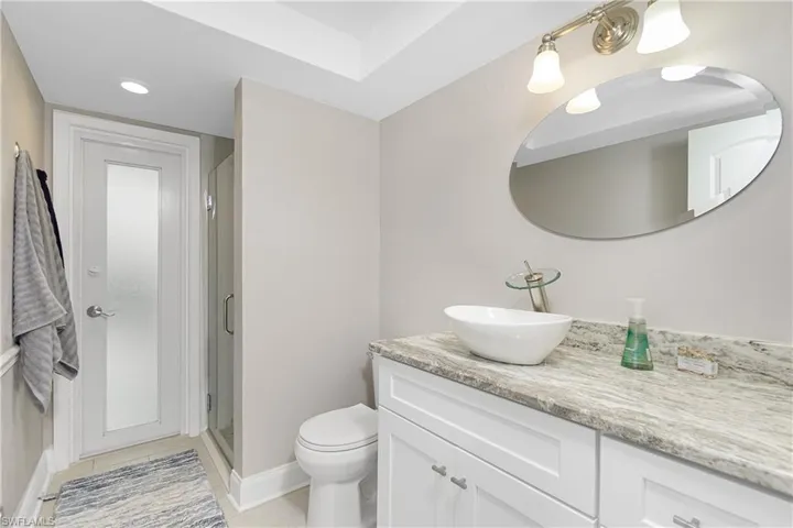 Bathroom with toilet, vanity, and an enclosed shower