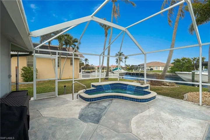 View of swimming pool with a patio area, a hot tub, a yard, a water view, and a lanai