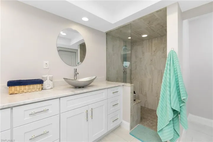 Bathroom featuring tile patterned flooring, vanity, and tiled shower