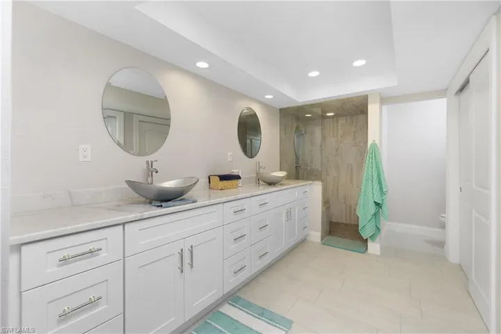 Bathroom featuring toilet, a tile shower, vanity, and a tray ceiling