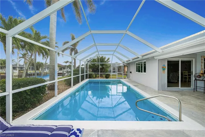 View of swimming pool with a water view, glass enclosure, and a patio