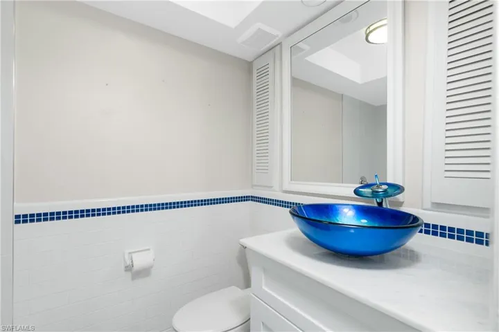 Bathroom with tile walls, vanity, and toilet