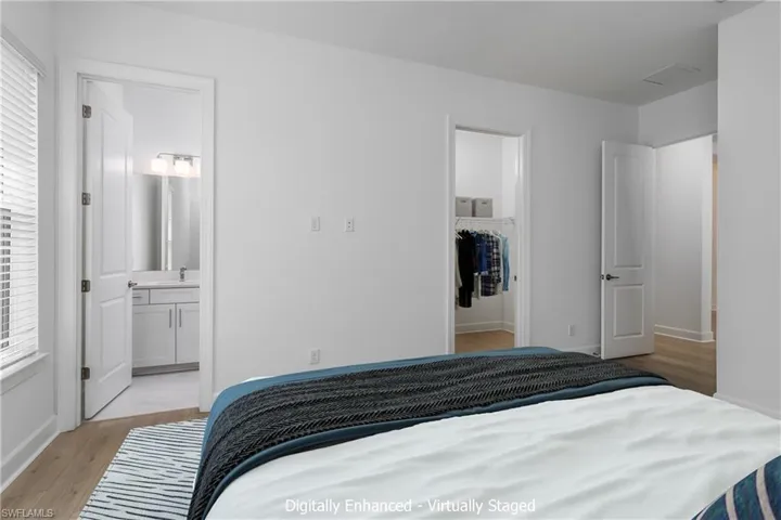Bedroom with a spacious closet, a closet, ensuite bathroom, and light wood-type flooring