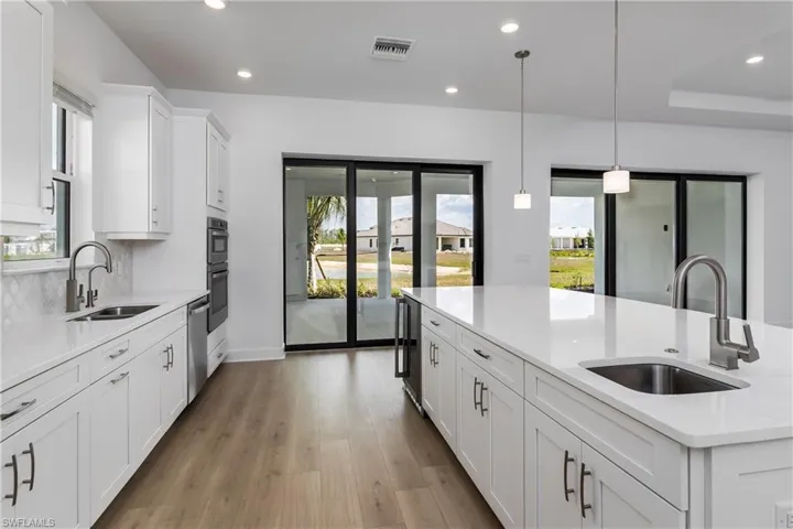 Kitchen with sink, light hardwood / wood-style floors, and decorative light fixtures