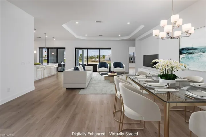 Dining area featuring a notable chandelier, wood-type flooring, and a raised ceiling