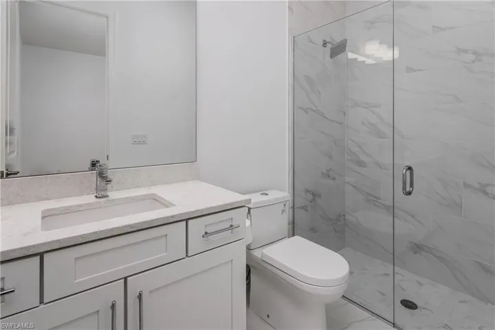 Bathroom featuring walk in shower, large vanity, toilet, and tile floors