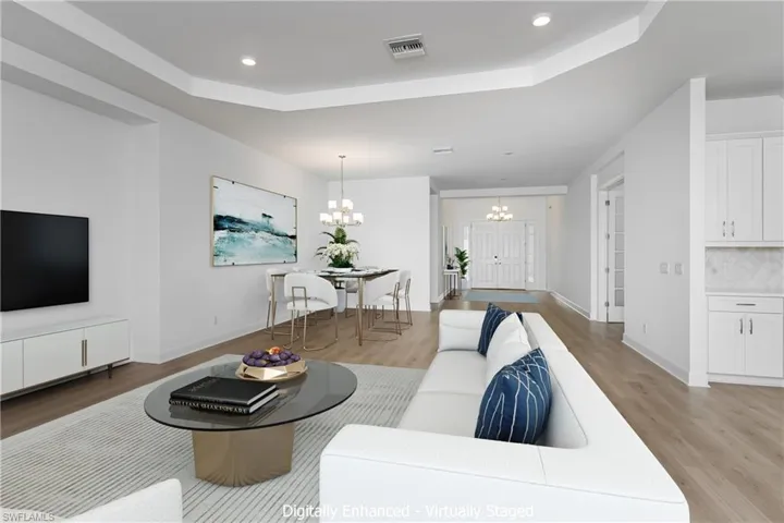 Living room with an inviting chandelier, a raised ceiling, and light hardwood / wood-style flooring