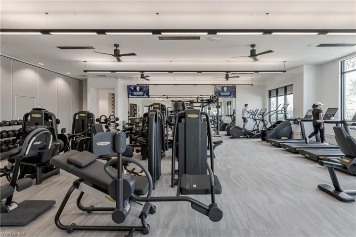 Exercise room with ceiling fan and light carpet