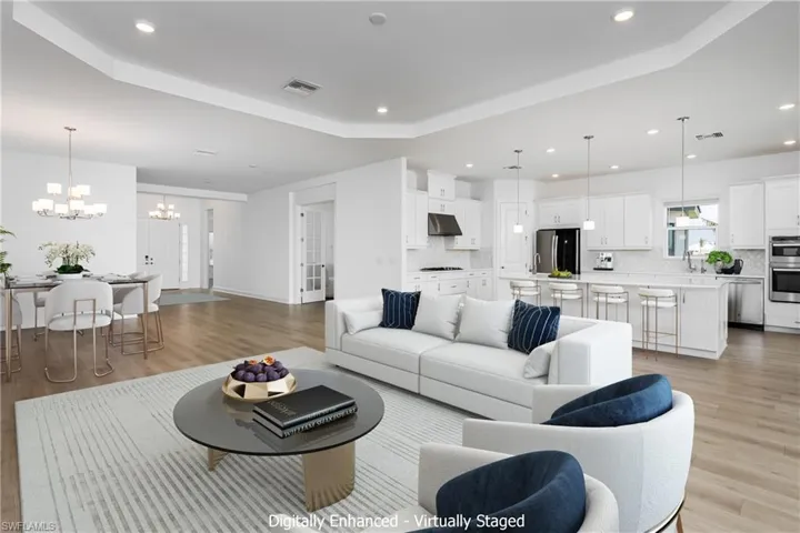 Living room with a tray ceiling, light hardwood / wood-style floors, sink, and a notable chandelier