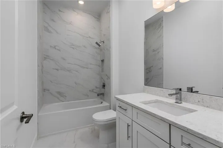 Full bathroom featuring tile flooring, vanity, toilet, and tiled shower / bath combo