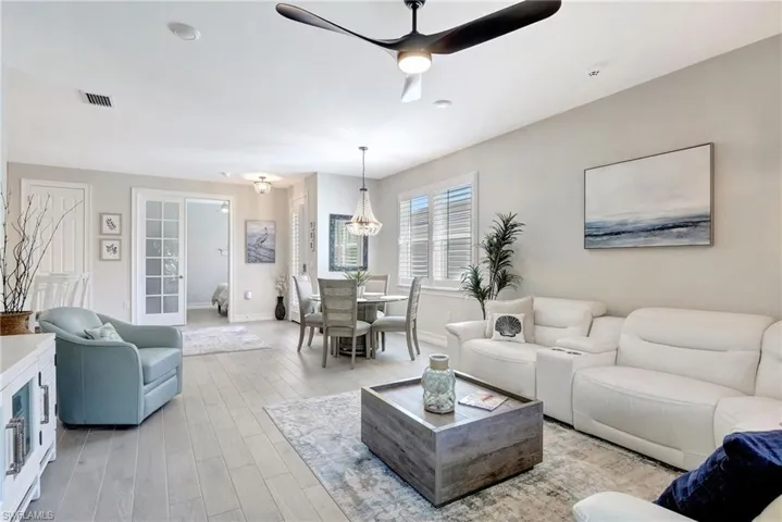 Living room with light hardwood / wood-style floors and ceiling fan with notable chandelier