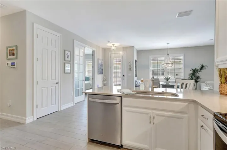 Kitchen featuring appliances with stainless steel finishes, light hardwood / wood-style flooring, hanging light fixtures, sink, and white cabinetry