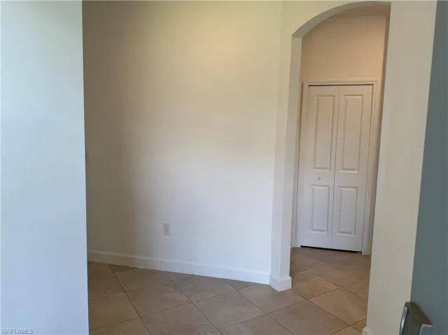 Arched doorway entry to a tiled hallway with a bi-fold closet door