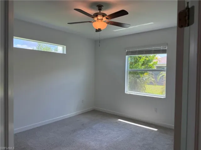 Carpeted room featuring a ceiling fan with integrated lighting, a horizontal clerestory window, and a standard window with blinds
