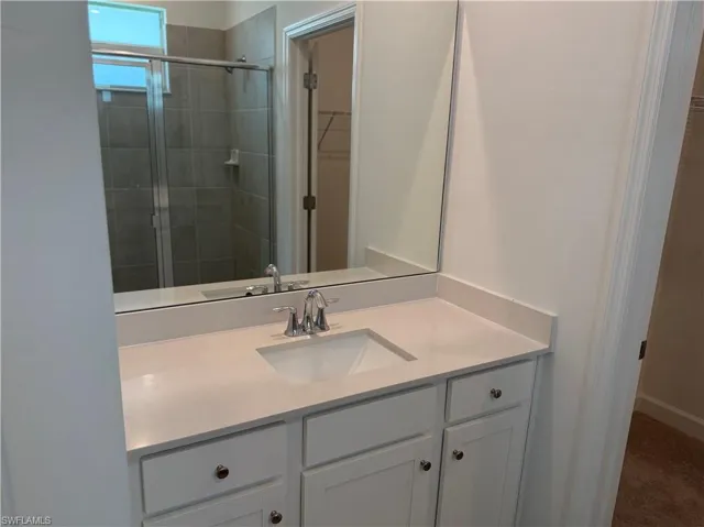 Bathroom vanity with an integrated sink, polished chrome faucet, and a large mirror