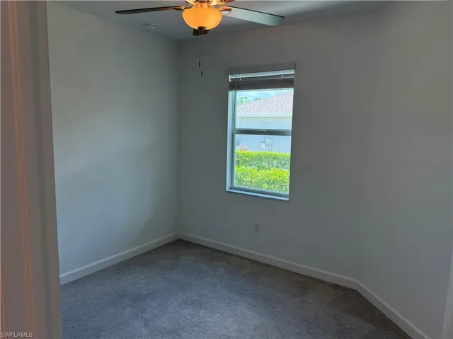 Clean interior room featuring light gray carpeting and white baseboards