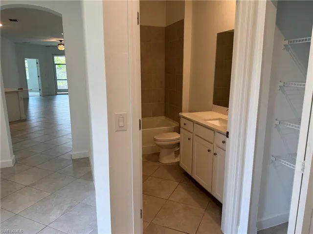 Bathroom featuring a white vanity with integrated sink, rectangular mirror, and tiled shower-tub combination
