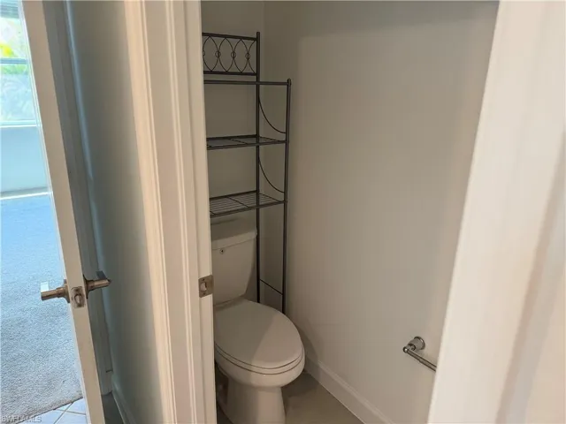 White toilet fixture with a polished chrome towel bar and neutral wall tones