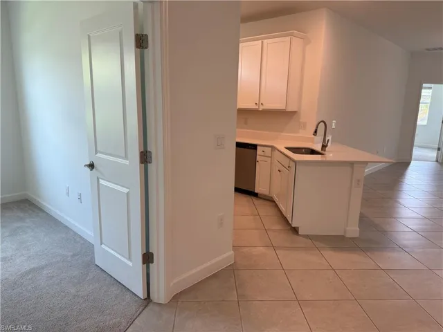 Contemporary kitchen featuring white cabinetry, a single-basin sink with a gooseneck faucet, light-toned countertops, and a stainless steel dishwasher