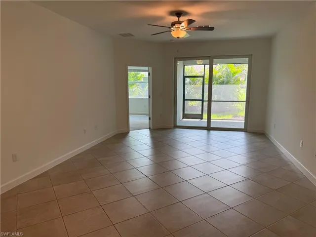 Spacious interior featuring neutral tone tile flooring, bright white walls, and a ceiling fan with integrated lighting