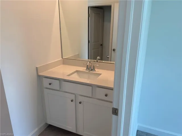 Bathroom vanity featuring a light-toned countertop, undermount sink, and contemporary faucet