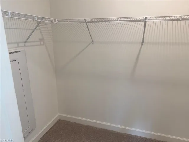Walk-in closet featuring wire shelving, wall-to-wall carpeting, and white baseboards