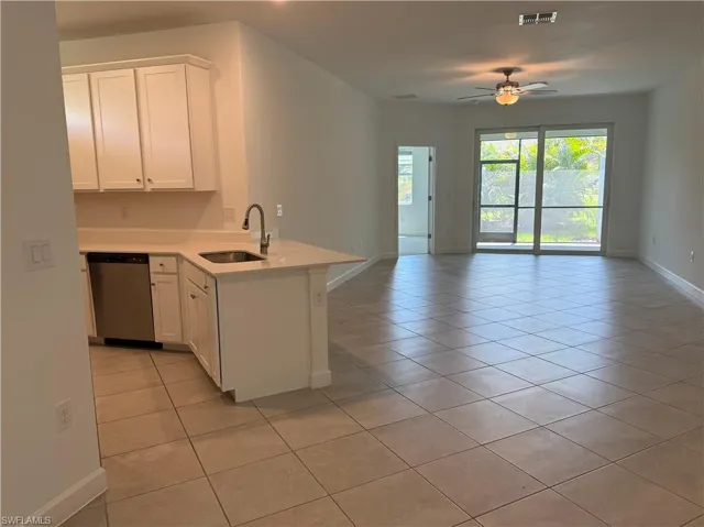 Open concept living space featuring a kitchen with white cabinetry, stainless steel dishwasher, and an undermount sink