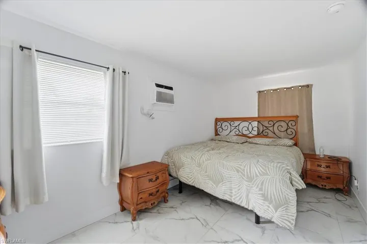 Bedroom featuring marble finish flooring and a wall mounted AC