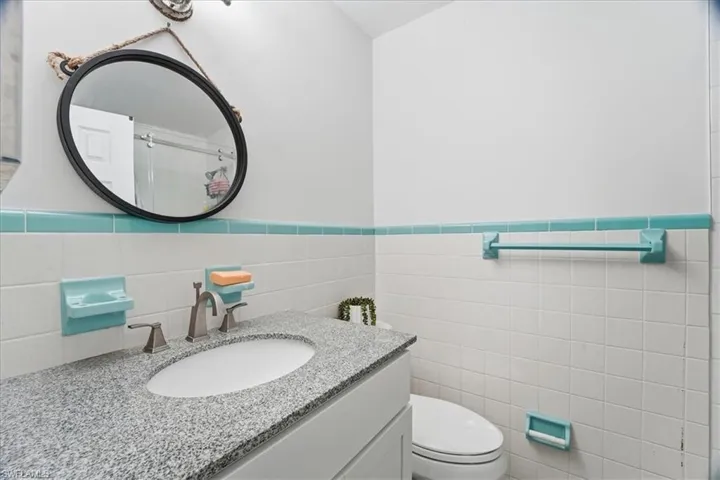 Bathroom featuring tile walls, vanity, and wainscoting