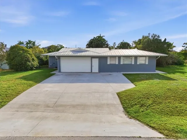 Ranch-style home with a front yard, concrete driveway, stucco siding, and an attached garage