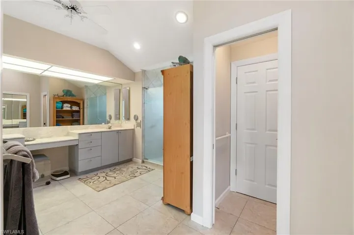 Full bathroom with vanity, a stall shower, vaulted ceiling, tile patterned flooring, and recessed lighting