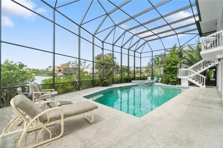 View of swimming pool with stairway, a patio area, a pool with connected hot tub, and a lanai