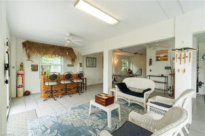 Living room with a ceiling fan, light tile patterned flooring, and a textured ceiling
