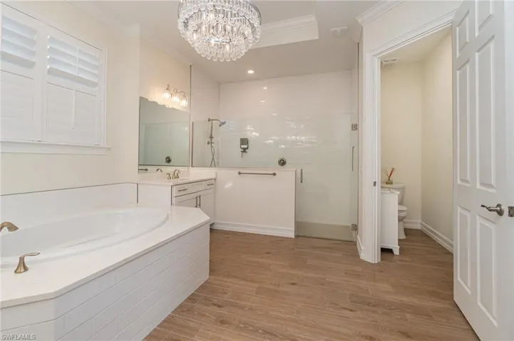 Primary bathroom featuring a notable chandelier, toilet, tiled  flooring, and crown molding