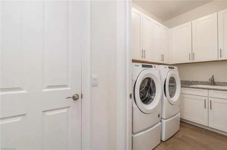 Laundry room featuring tiled floors, cabinets, separate washer and dryer, and sink