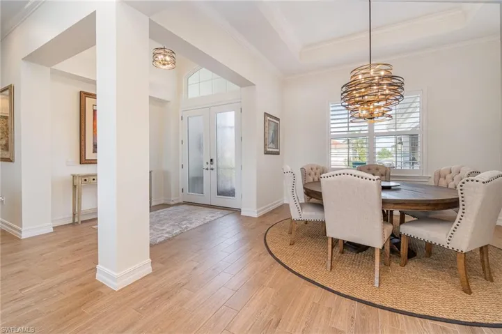 Dining area featuring   tiled flooring, a tray ceiling, crown molding, and a chandelier