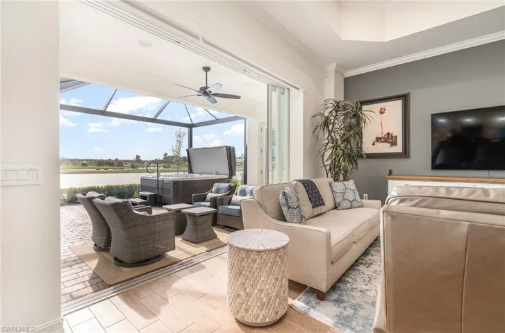 Living room featuring ceiling fan, a water view, tiled floors, and crown molding
