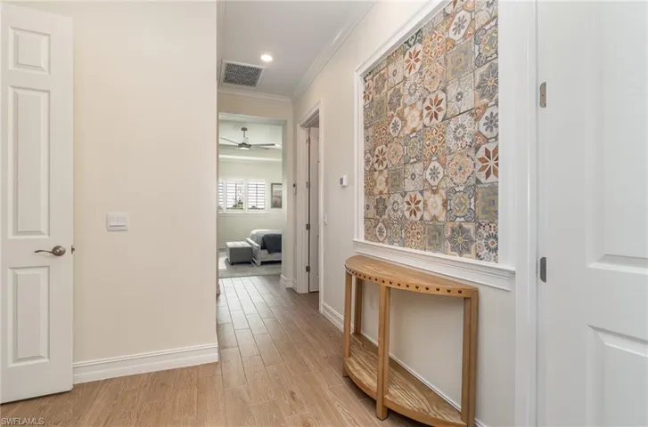 Primary bedrm/bathrm Hallway with crown molding and light flooring