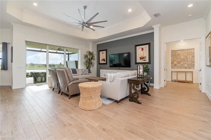 Living room with ceiling fan, tiled floors, crown molding, and a tray ceiling