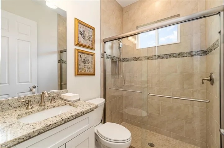 Bathroom featuring vanity, an enclosed shower, and toilet