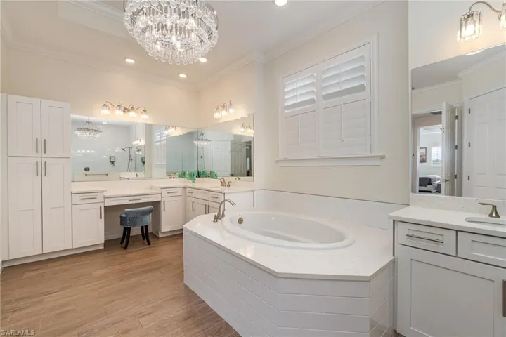 Primary bathroom featuring a wealth of natural light, tiled  floors, a notable chandelier, and crown molding