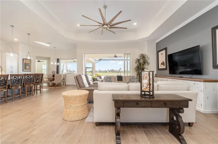 Living room with a tray ceiling, crown molding, ceiling fan and titled flooring