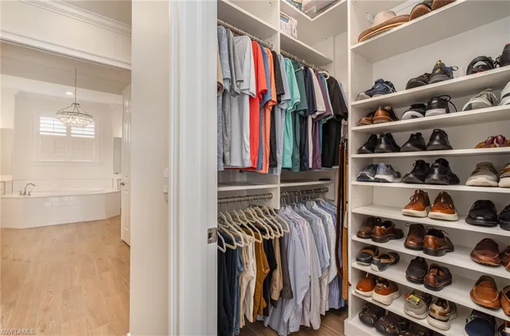 Spacious closet with custom shelving, tie, belt holder, and tiled flooring